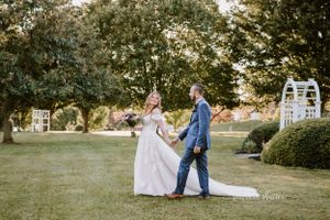 Two people dancing on a lawn at sunset with a garden arch and greenery in the background. Rockfield Manor