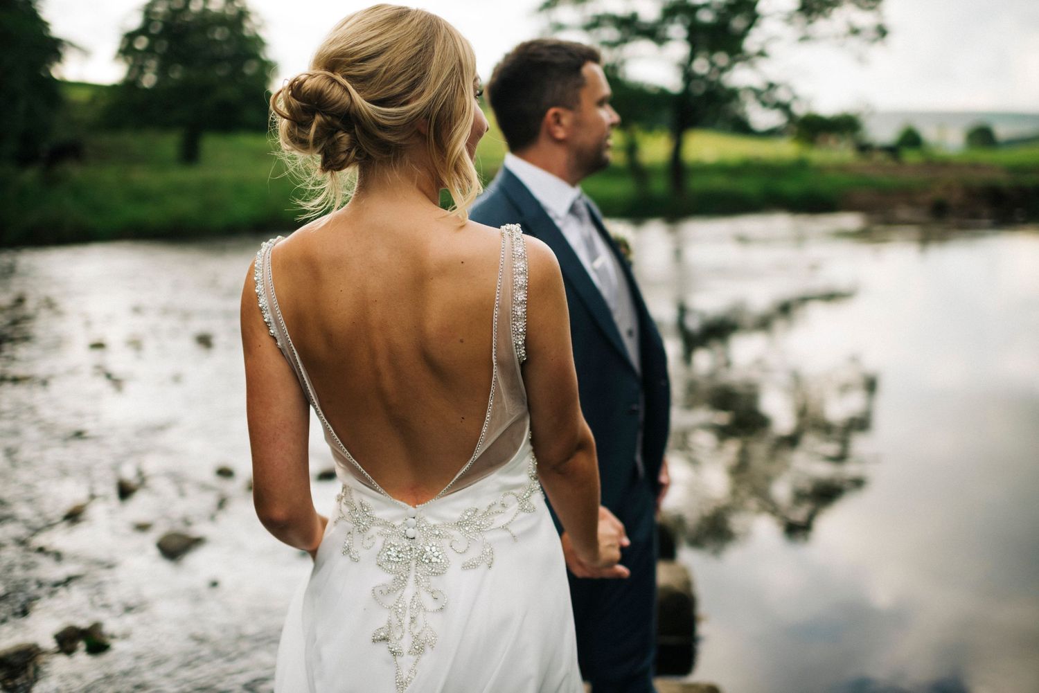 Lakeside wedding portraits with reflective water and natural outdoor scenery.
