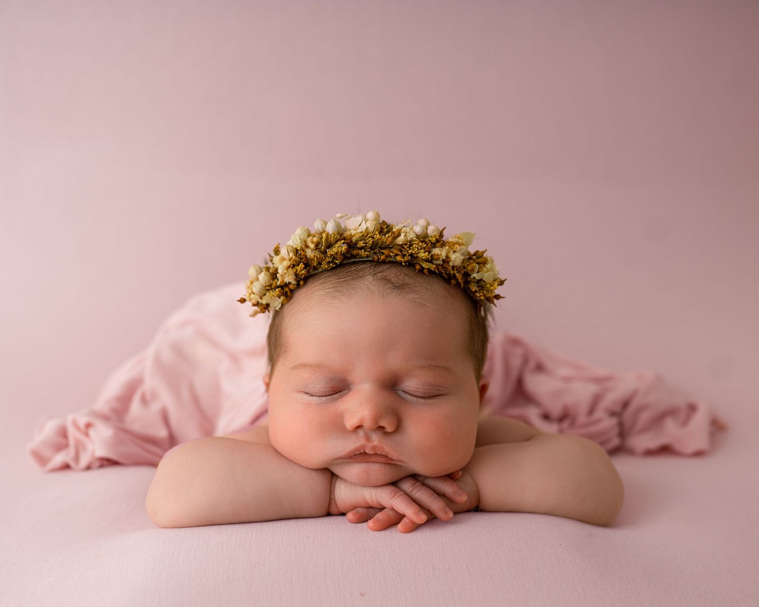 baby girl on pink backdrop with floral headband photographed by newborn photographer swansea