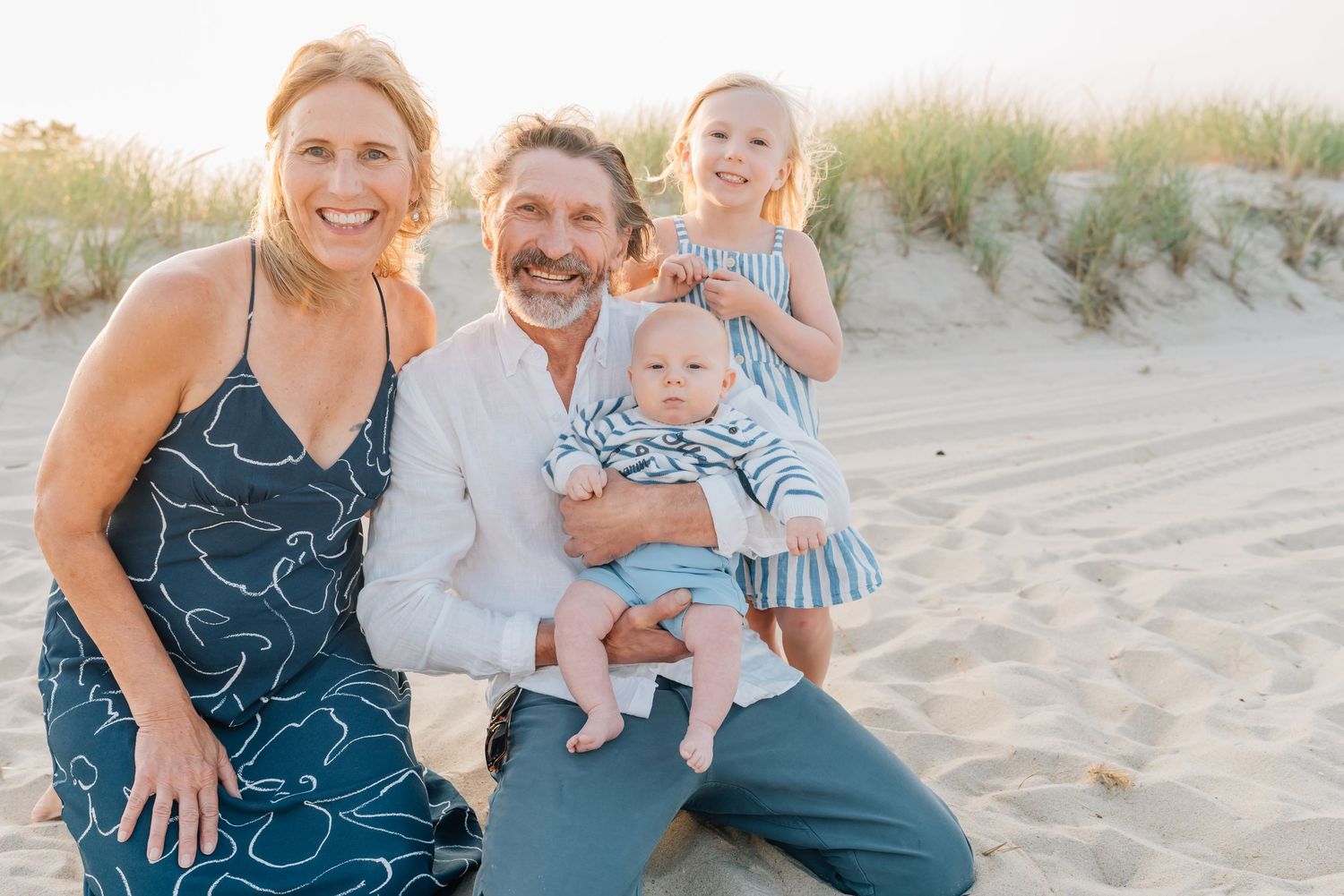 Grandparents snuggle together with their grandchildren on the NJ beach as the sun sets.