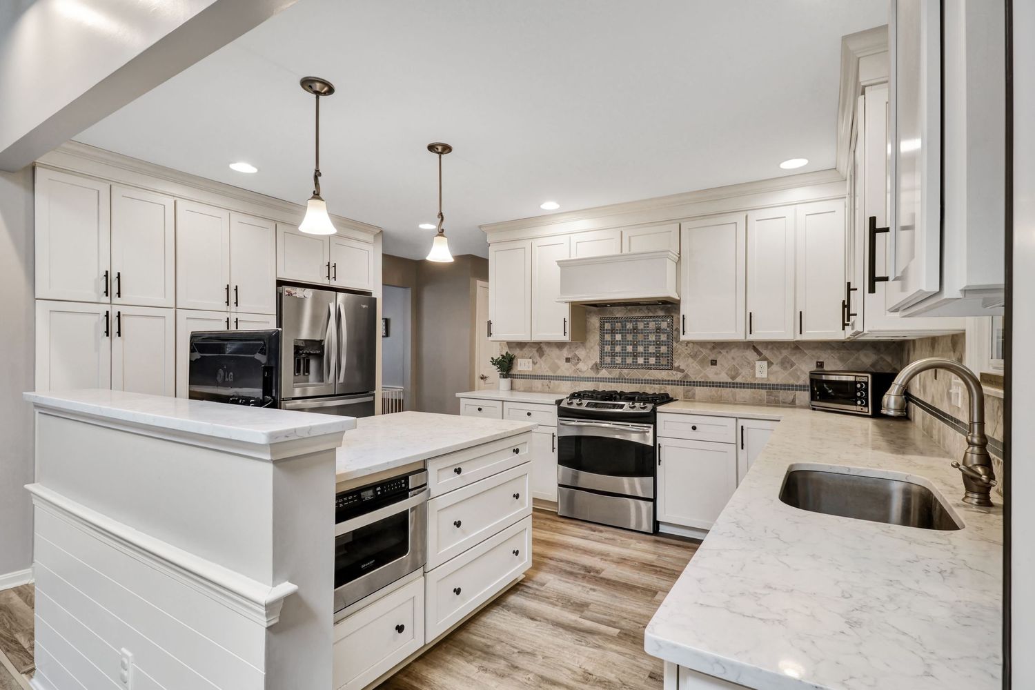 Modern kitchen renovation featuring white cabinets, stainless appliances, and hardwood floors in an open concept layout.