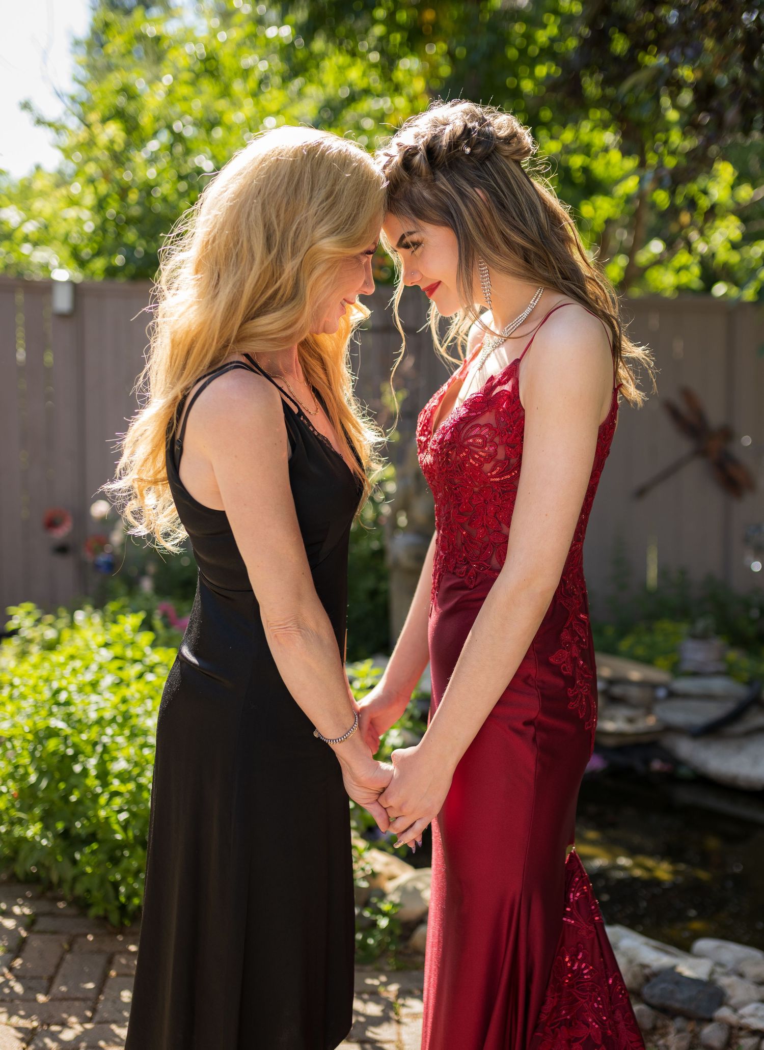 Two people in formal dresses sharing an intimate moment in a garden setting.