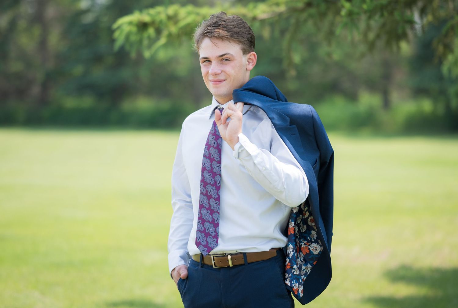 Person in business attire carrying suit jacket over shoulder in outdoor setting.