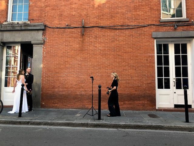 Artistic wedding composition against red brick wall with photographer in frame.