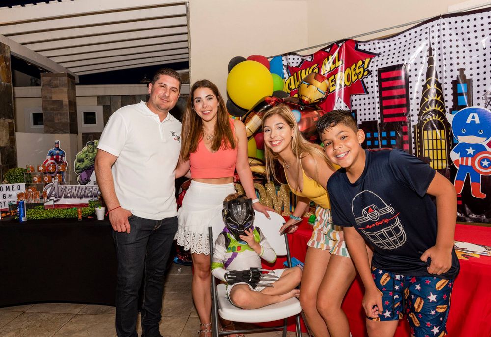 Casual group photo at themed party with decorative backdrop and displays.