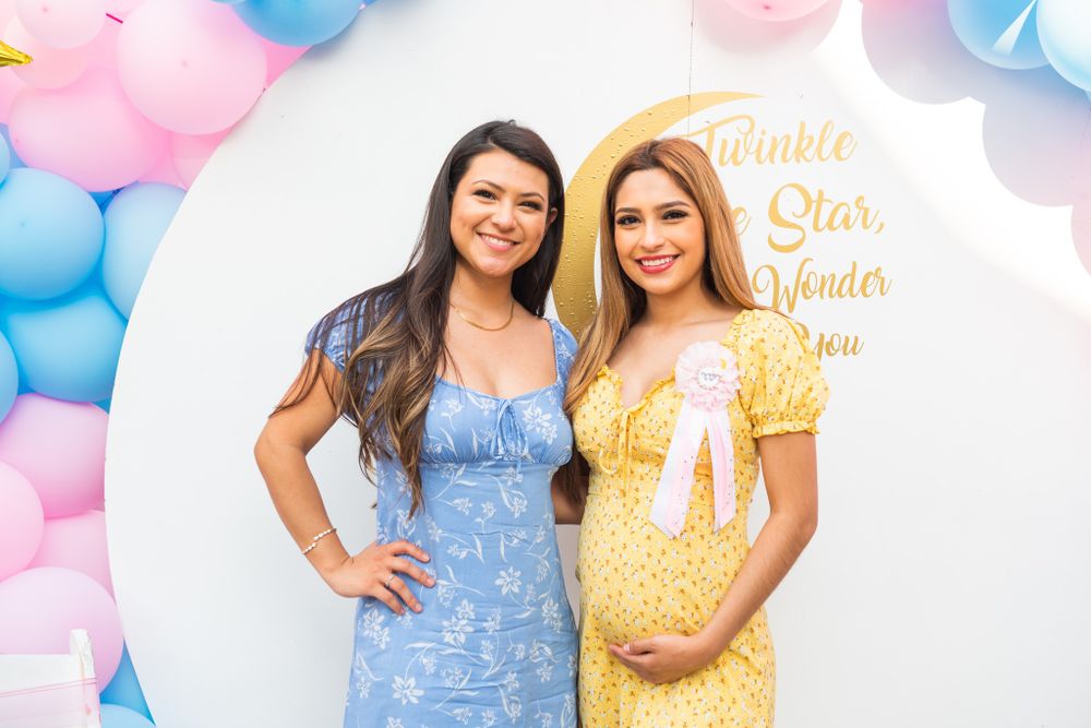 A gender reveal party setup with pink and blue balloon decorations against a white backdrop.