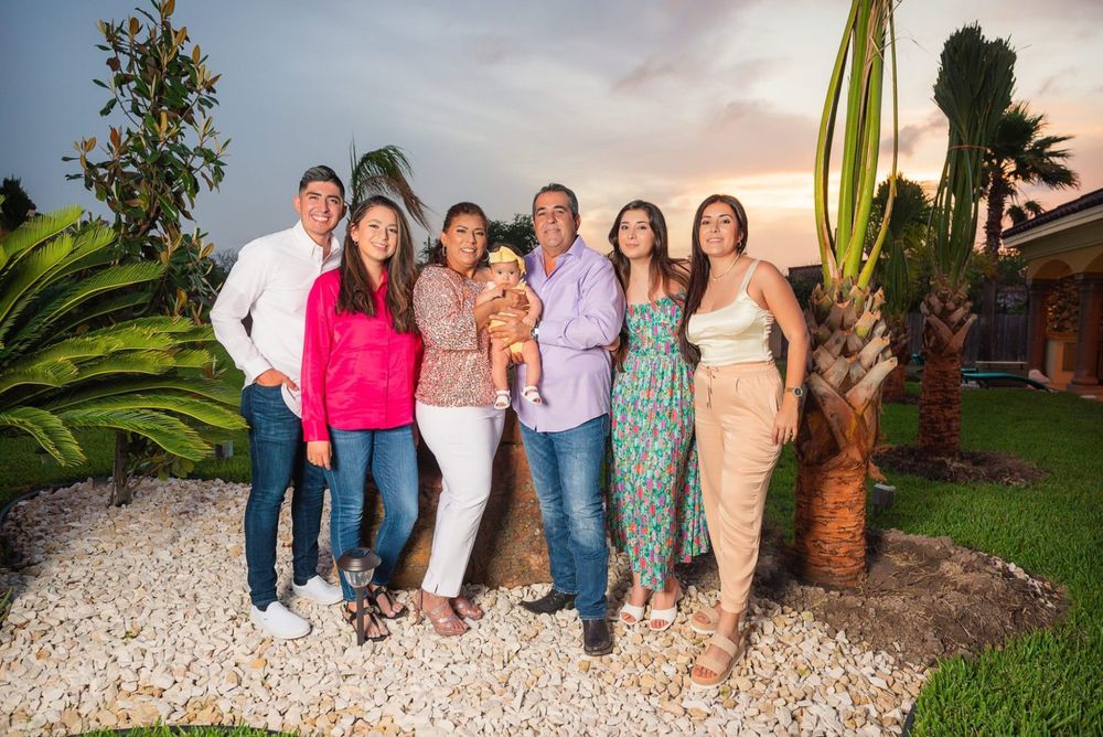 Group poses together at sunset by tropical palm trees and white gravel landscaping.