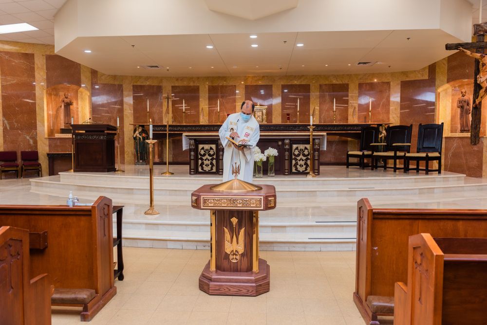 A clergy member stands at the altar of a modern Catholic church during a service.