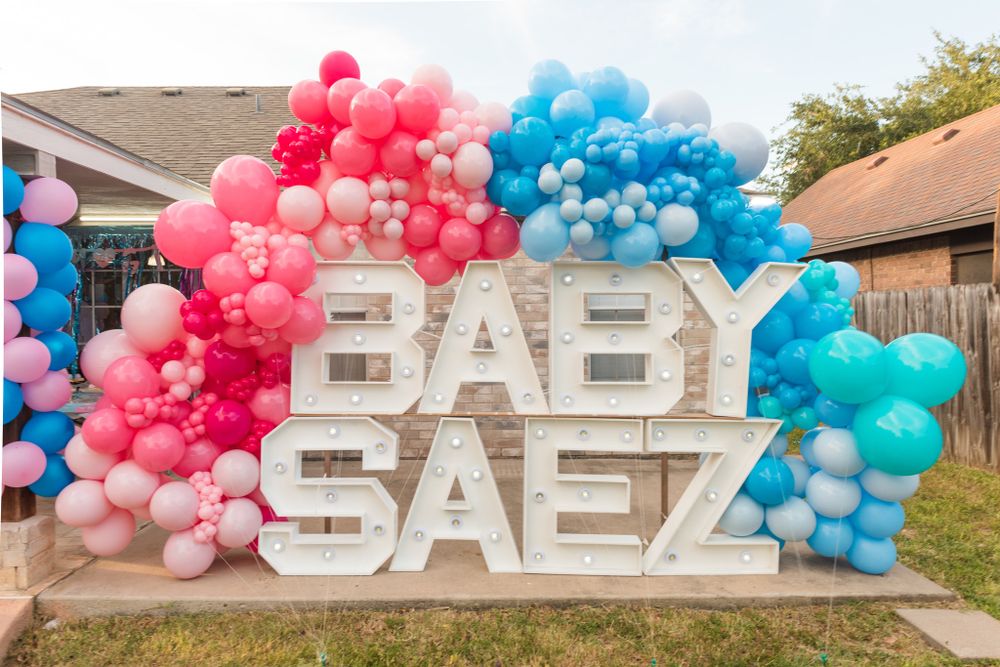 Large 'BABY SAEZ' text display with pink and blue balloon arch decoration.