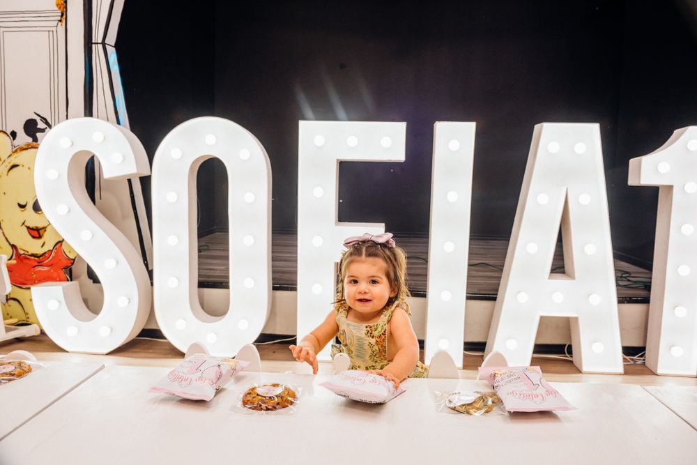 A young girl lying on the floor next to large white SOFIA letters at a celebration.