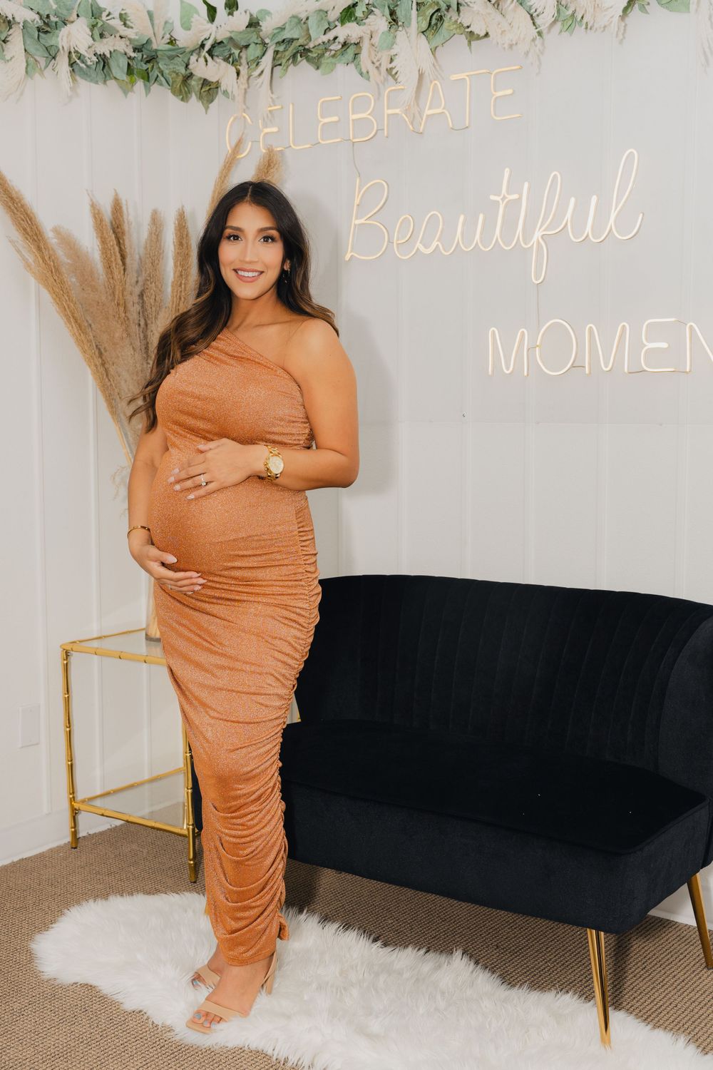 Baby shower setup with a cream colored couch and neon sign reading 'Celebrate Beautiful Moments'.