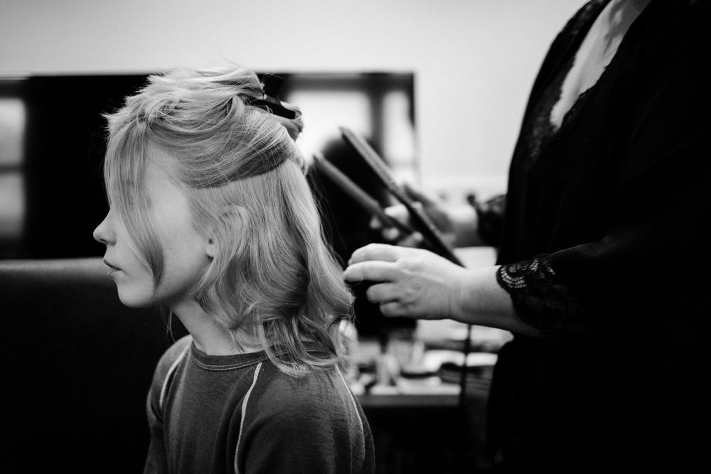 A black and white photo of a hairstyling session in progress.