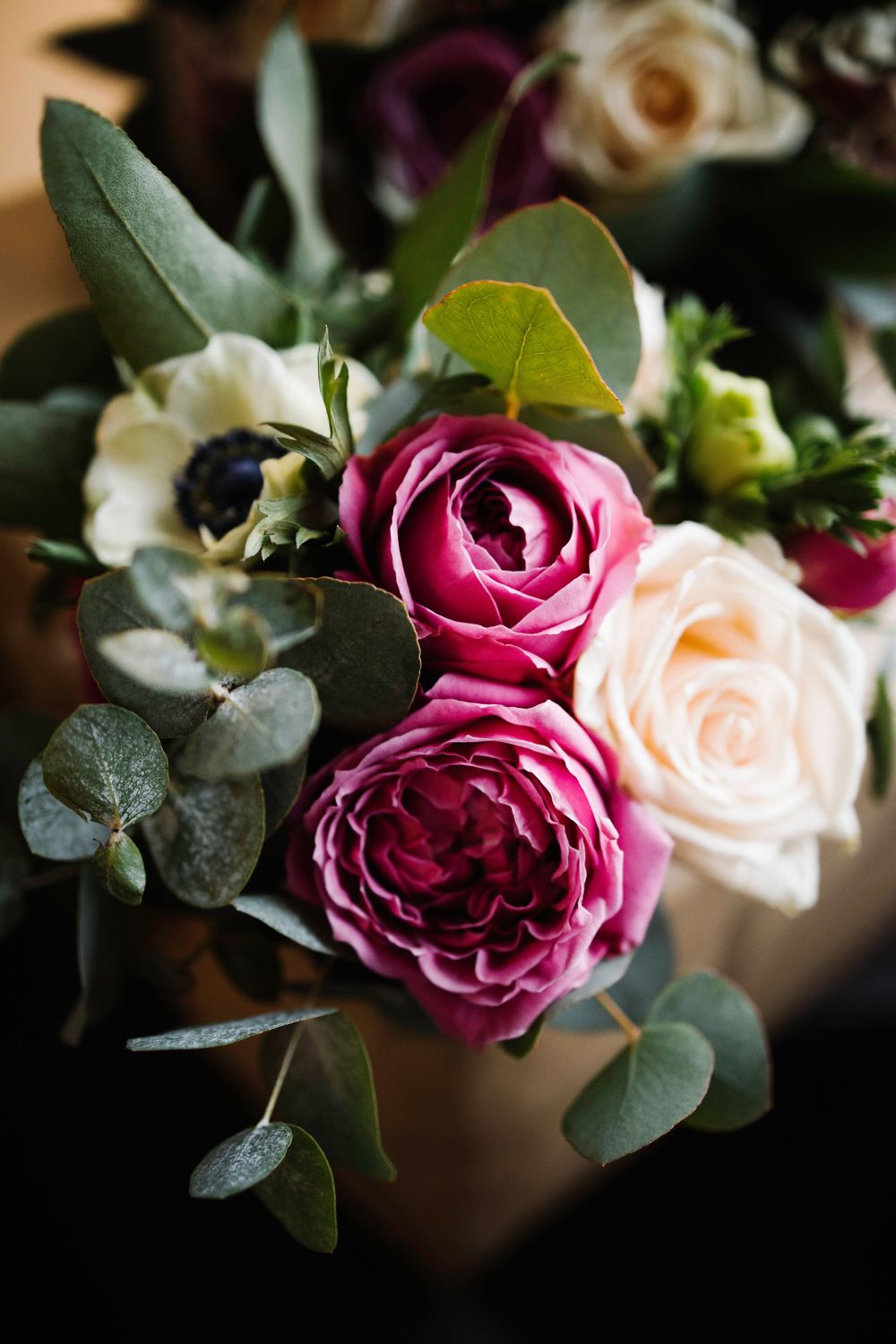 Pink and cream roses with eucalyptus leaves in an elegant floral arrangement.