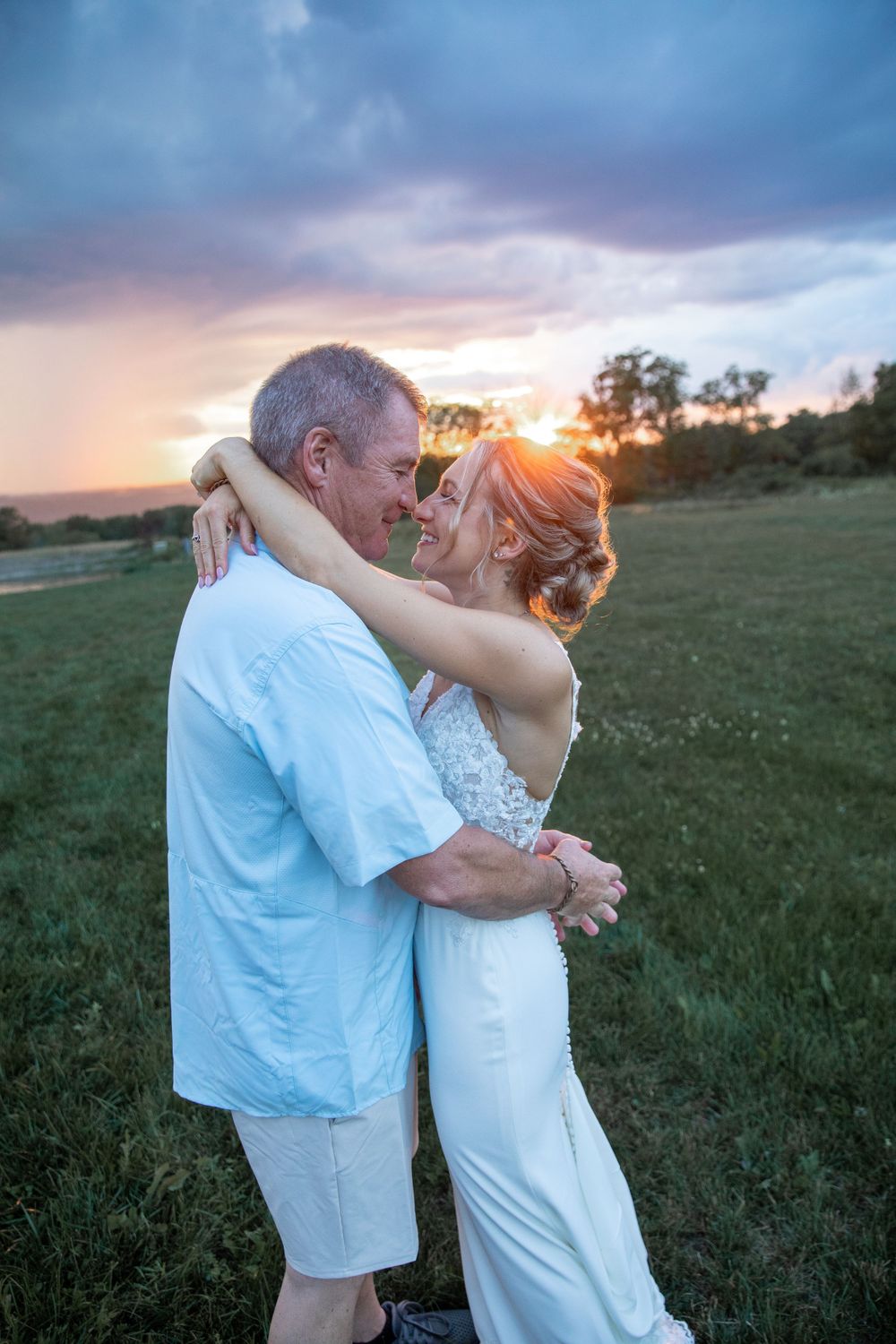 Couple dancing together in field during golden hour sunset.