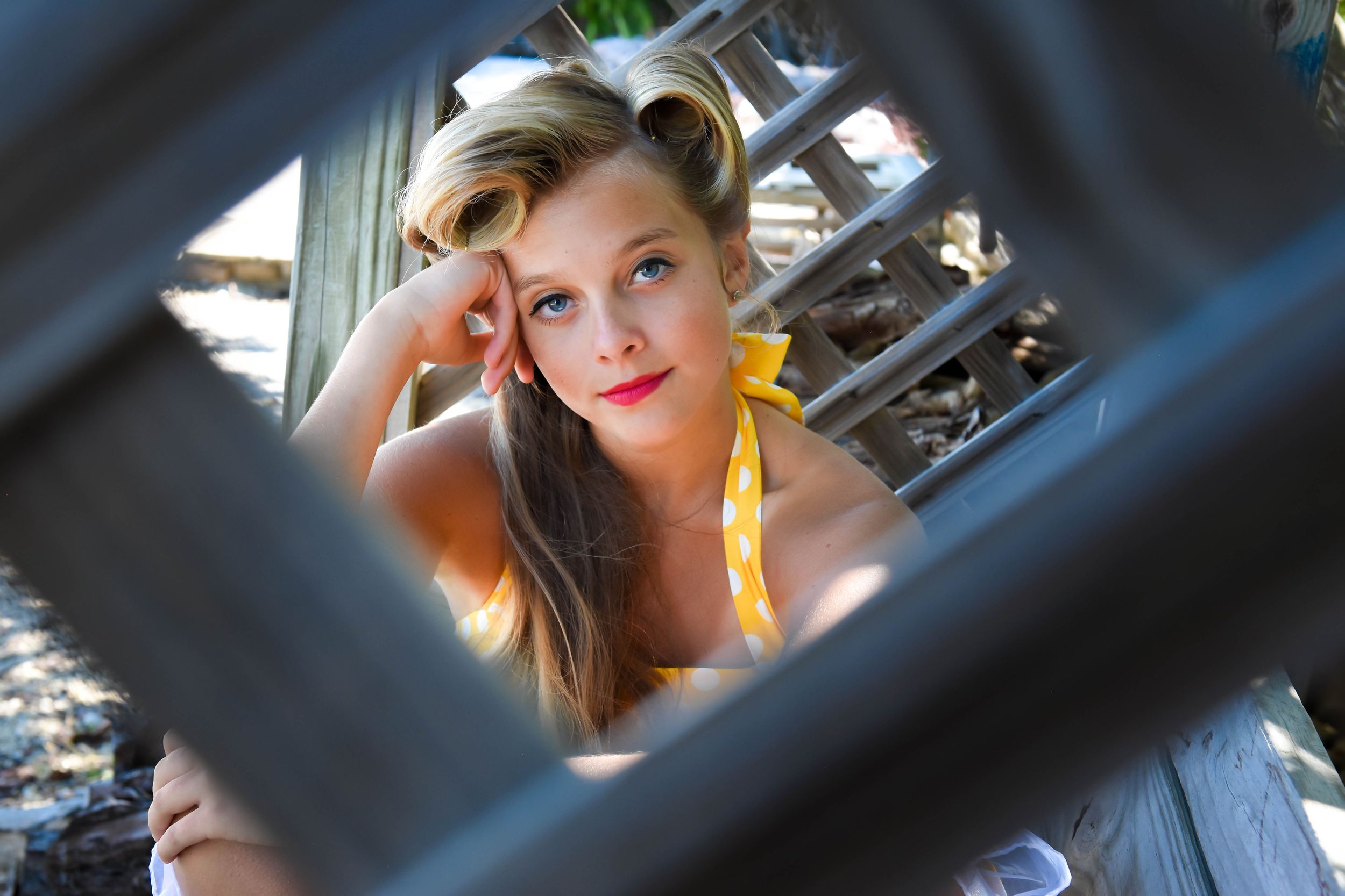 Creative portrait through architectural elements with warm lighting and artistic framing.