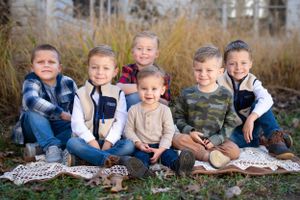 Group of young boys in casual attire sitting together outdoors on a blanket. Family Photographer Batavia Cincinnati Ohio