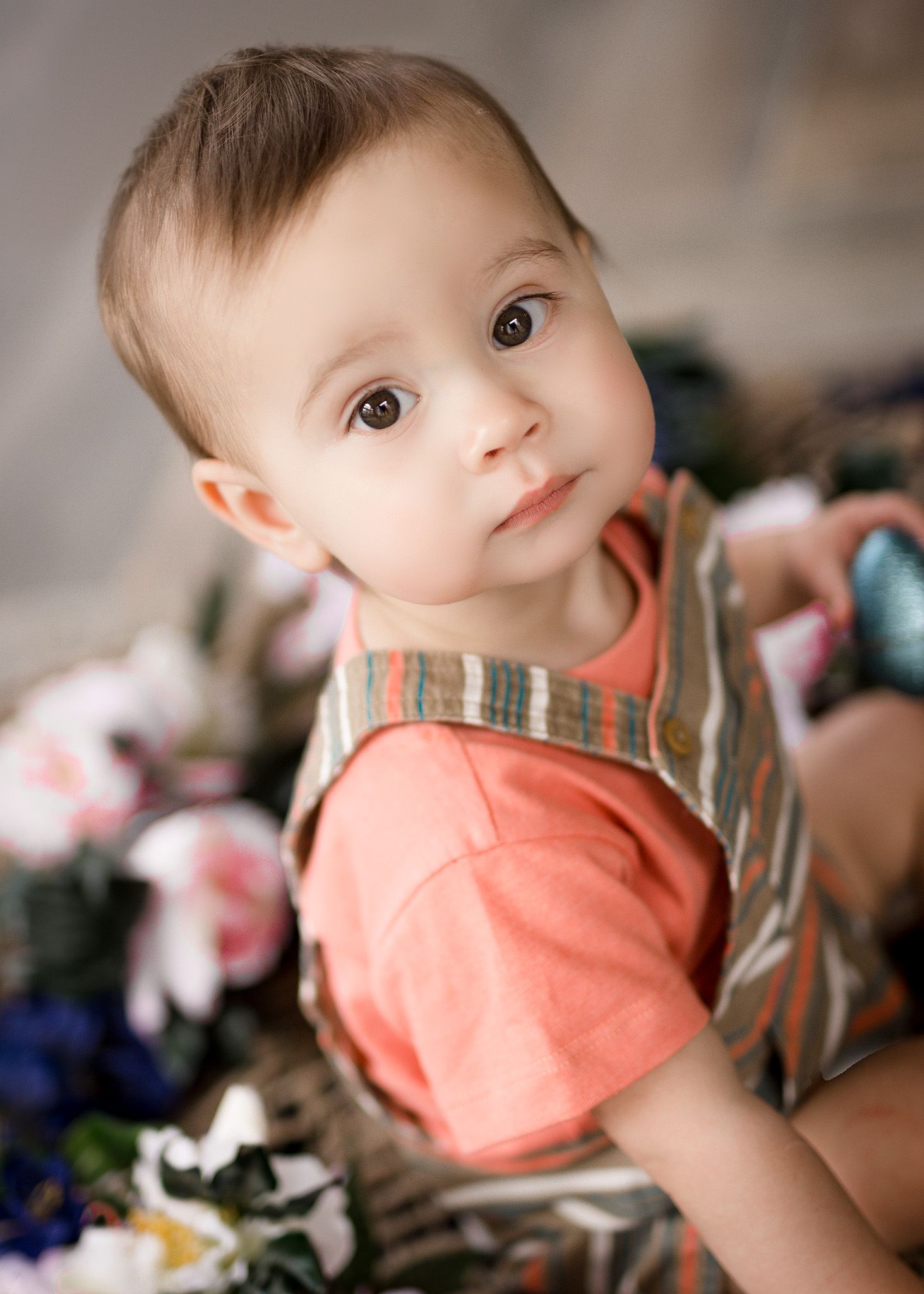 Close-up portrait of a baby wearing a coral t-shirt against a soft background with toys. Family photographer Batavia Cincinnati Ohio