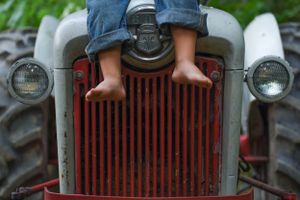 Small feet in jeans standing on vintage red tractor grill. Family Photographer Batavia Cincinnati Ohio
