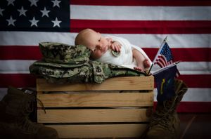 Military boots and camouflage uniform arranged with American flag backdrop. Newborn Photographer Batavia Cincinnati Ohio