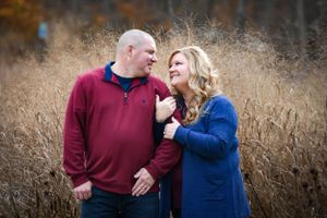 Couple laughing together in tall grass during golden hour. Family Photographer Batavia Cincinnati Ohio