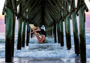 Silhouette of person jumping between pier pillars at sunset. Dance Photographer Batavia Cincinnati Ohio