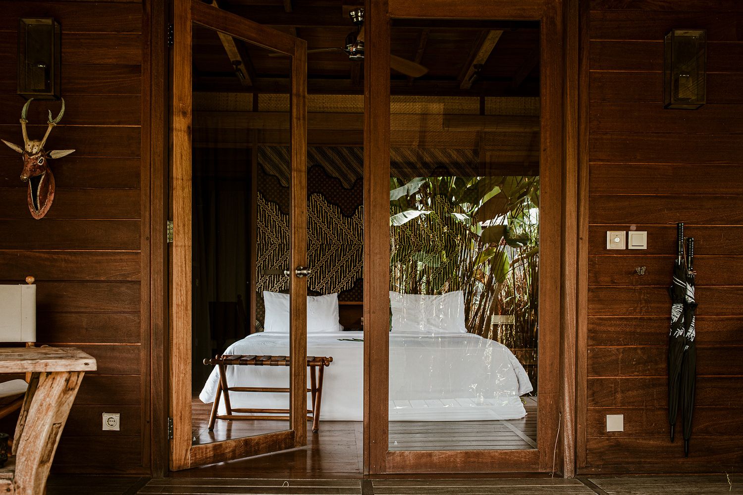 View from the terrace into a hotel bedroom at the Sanak Retreat in Bali with the reflection of the outdoor greenery