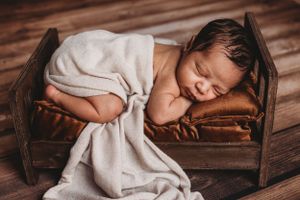 Newborn baby photo in little bed with blanket. Baltimore newborn photographer