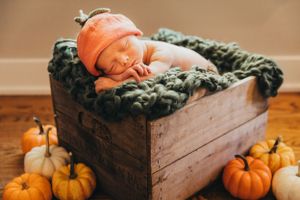 Fall posed newborn baby boy as pumpkin in patch