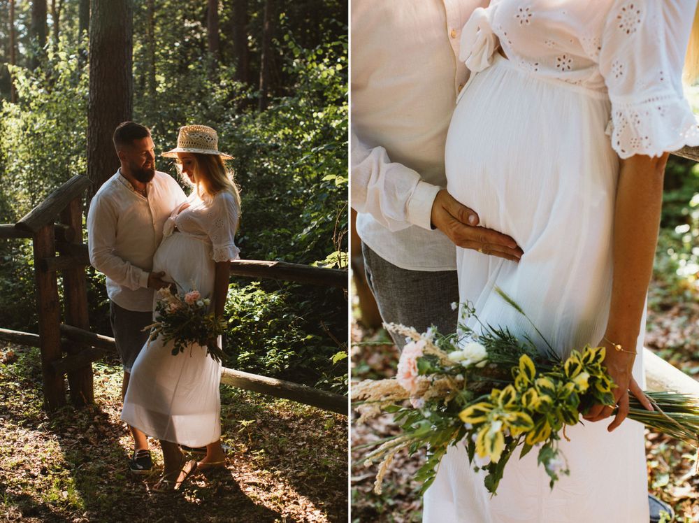 Couple embracing in sunlit forest, pregnant woman in white dress holding bouquet.