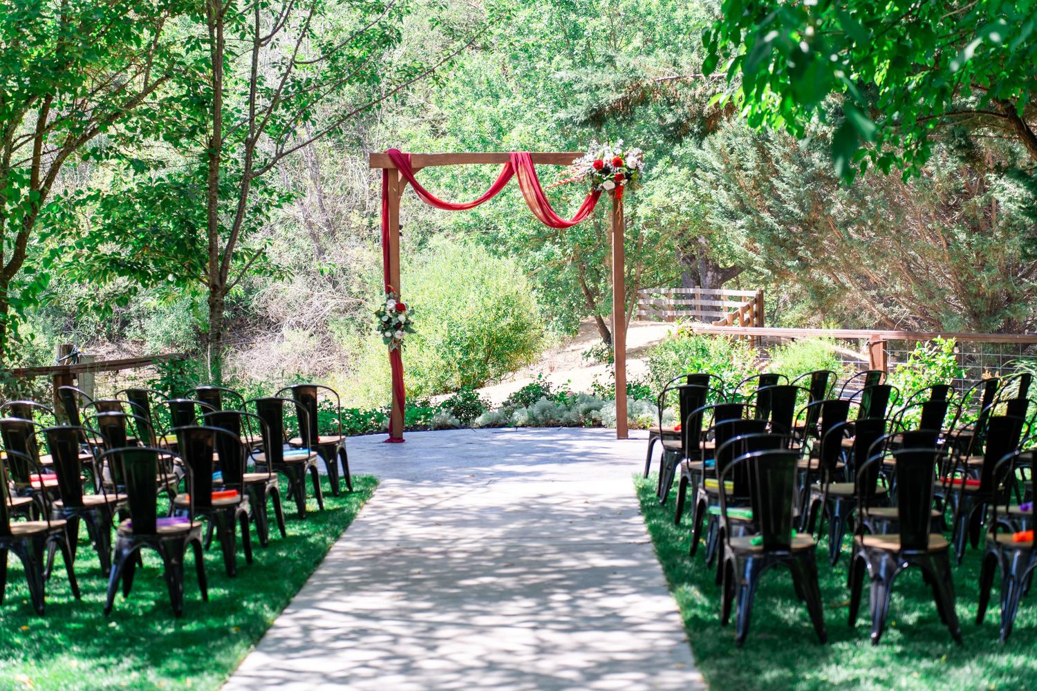 ceremony set up with arch and burgundy material and floral arrangements