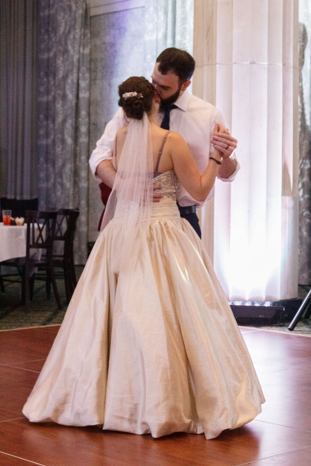 Couple sharing their first dance in formal attire at an elegant venue.
