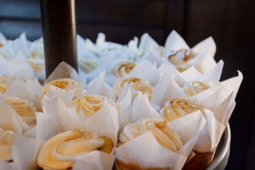 Freshly baked cupcakes with vanilla frosting arranged in white paper liners on a display.