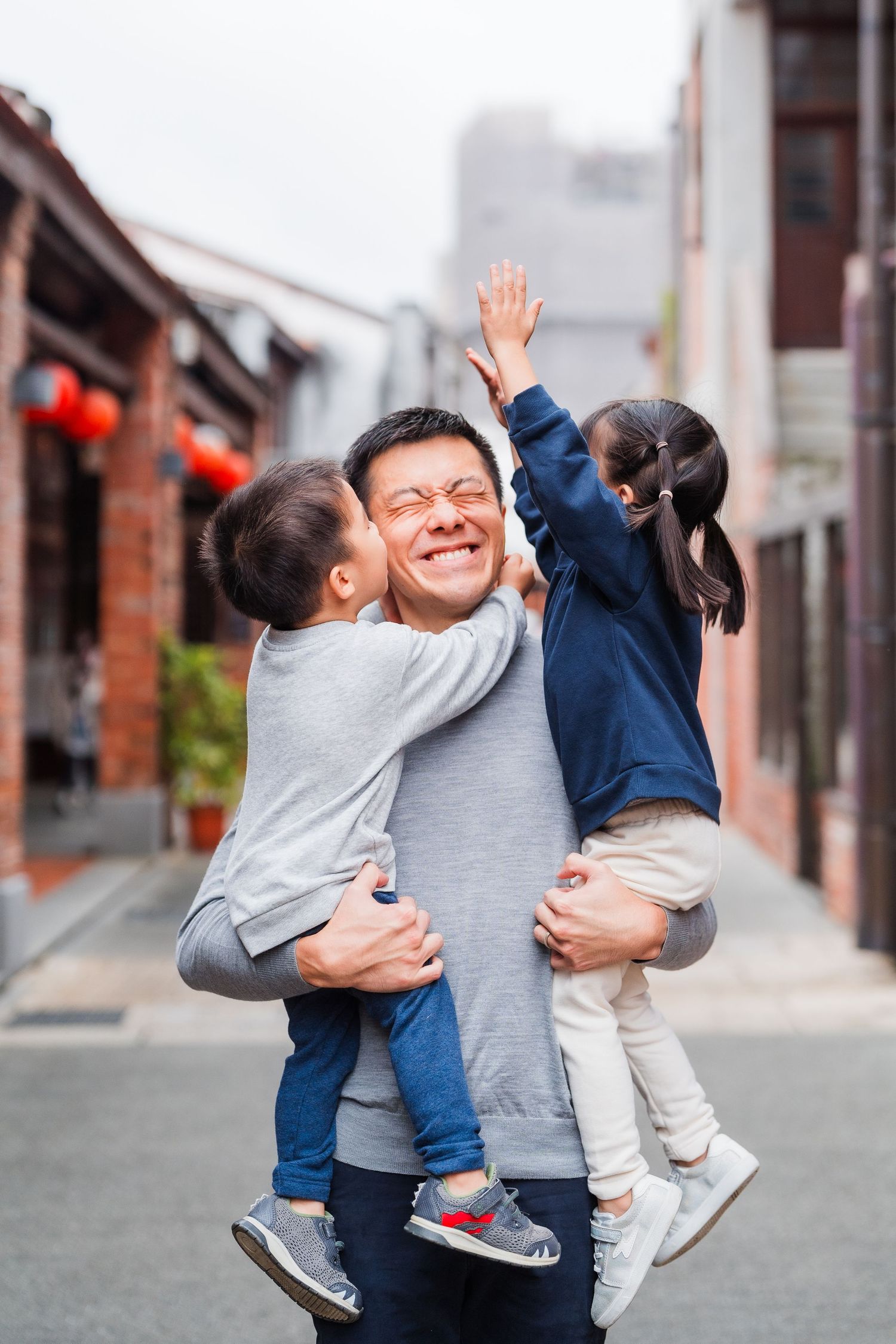 Parent and children sharing joyful moment together on urban street.