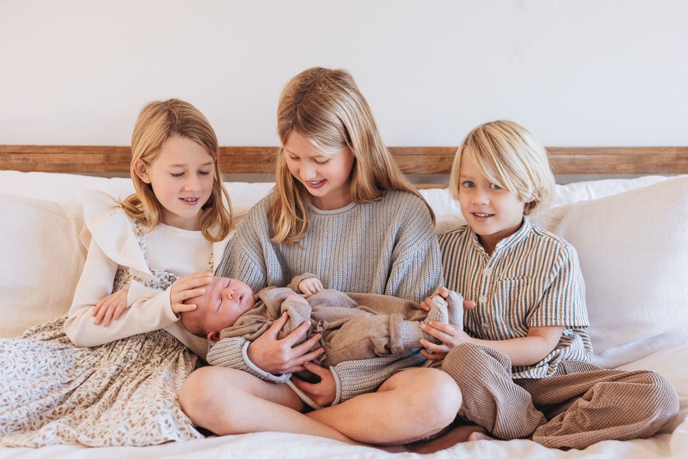 Family members in matching gray outfits sitting together on white bedding.