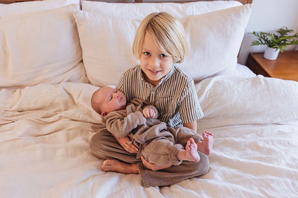 A tender moment with a newborn baby on white bedding.