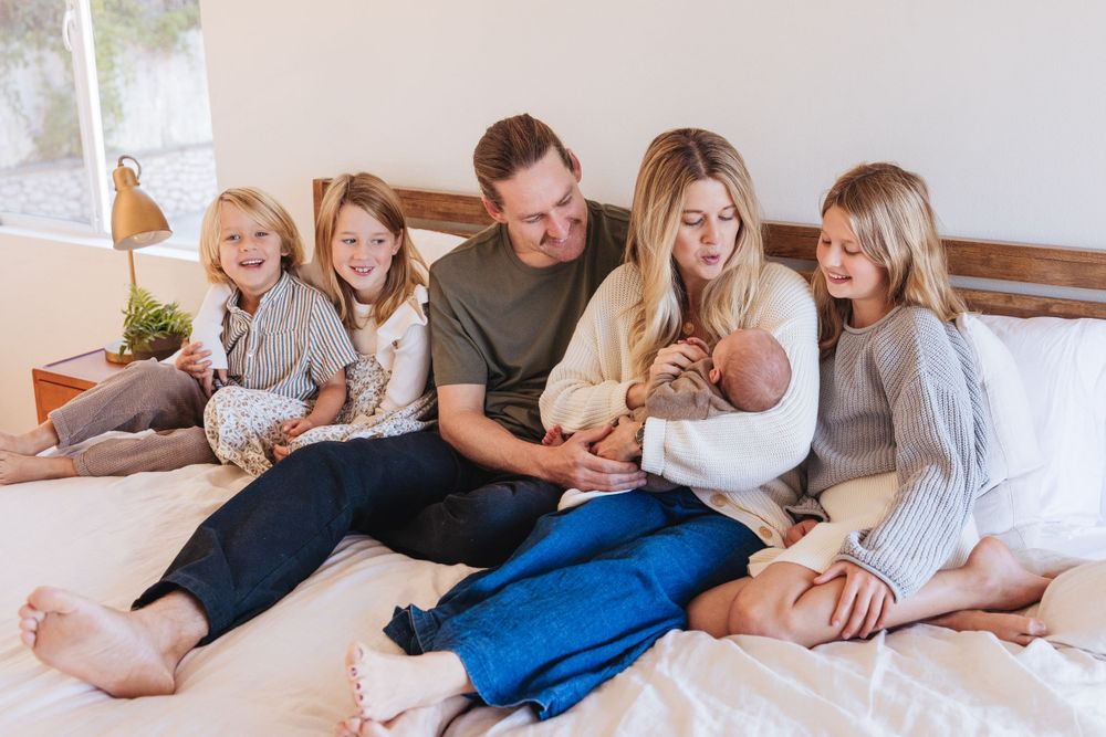 Casual family moment captured on a comfortable bed with natural lighting.