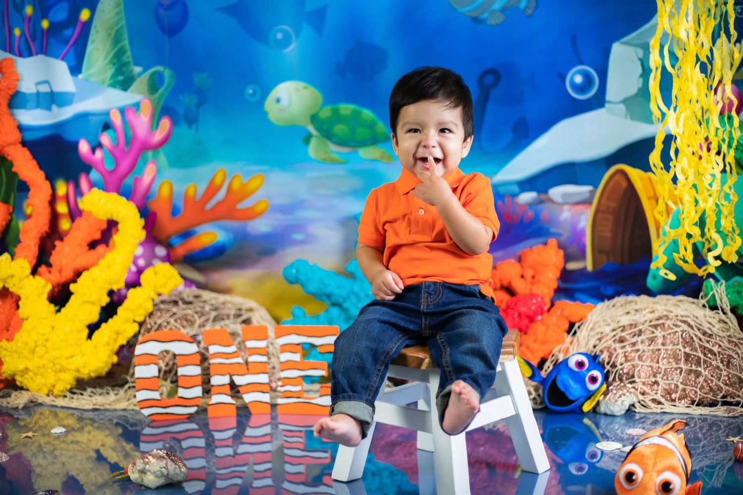 Underwater themed birthday backdrop with colorful coral decorations and sea creatures.
