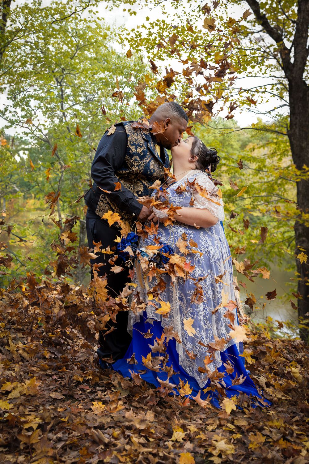 A romantic wedding photo with falling autumn leaves creating a magical effect around the couple.