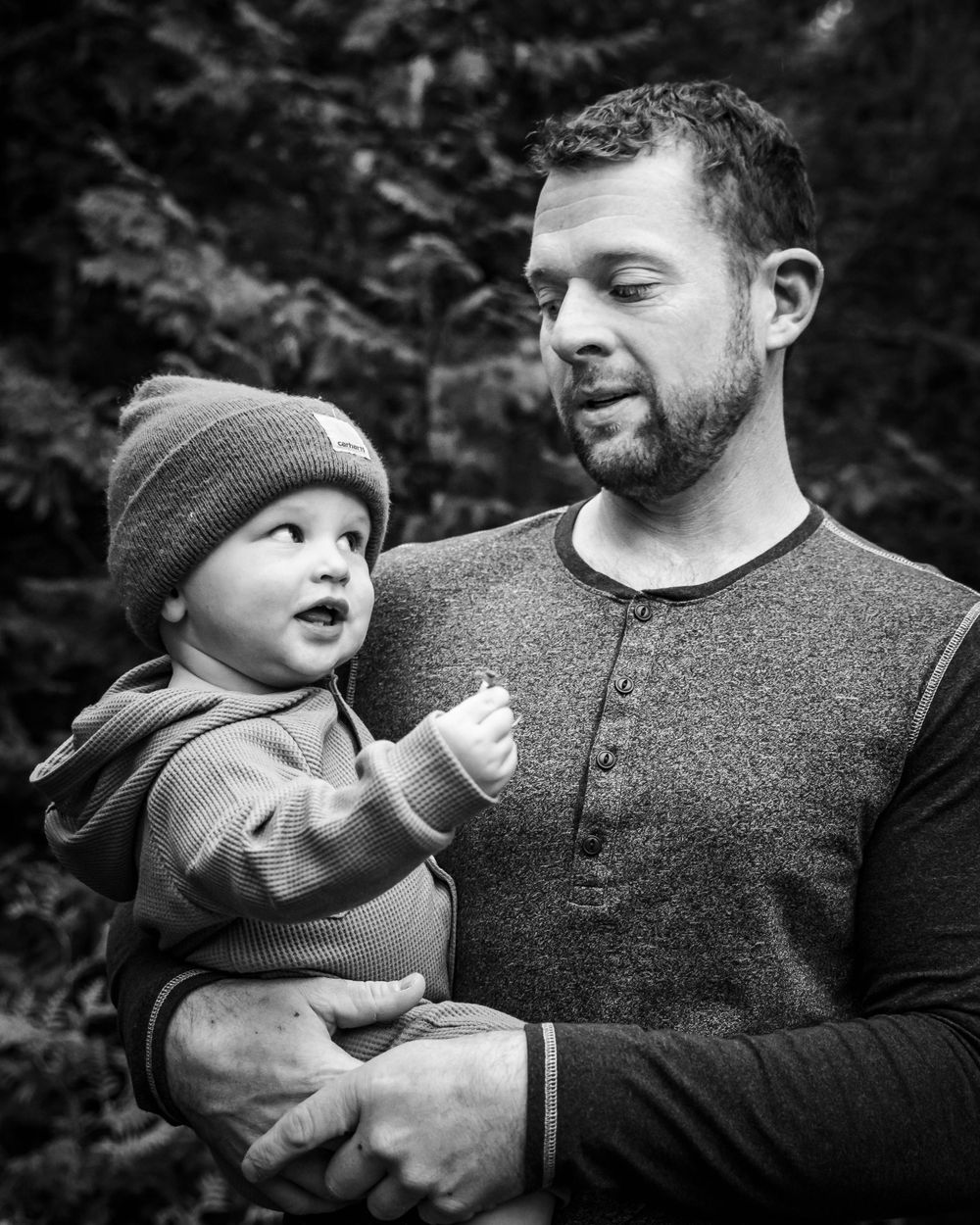 An intimate black and white portrait captured in a forest setting.