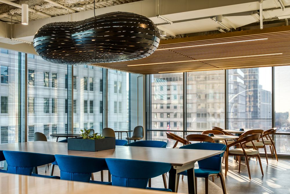 Contemporary office lounge with blue tables, wooden chairs and decorative sphere light fixture.