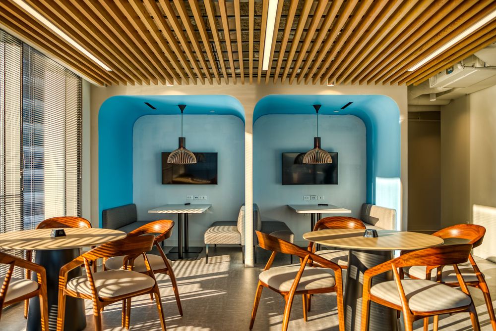 Stylish breakout area featuring turquoise alcoves, wooden chairs and pendant lighting.