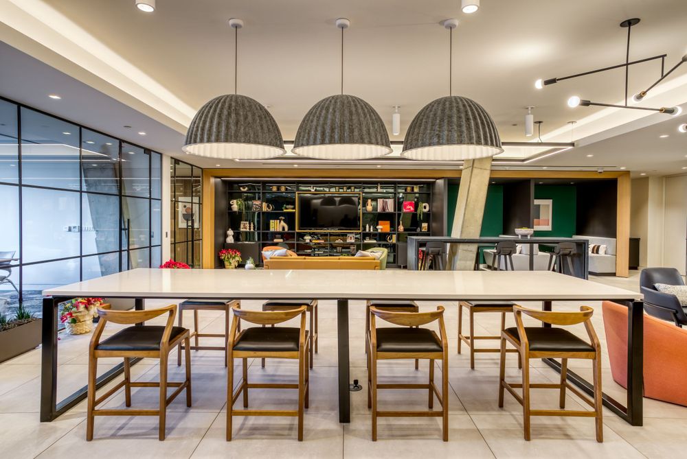 Modern office bar area with hanging dome lights and wooden bar stools.