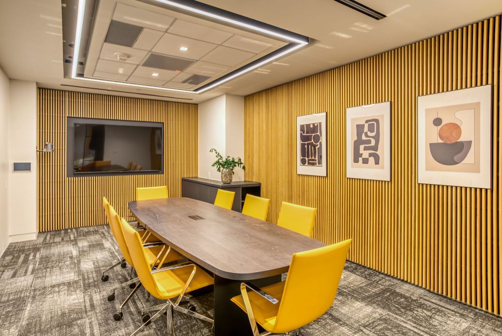 Conference room with yellow chairs, wood paneled walls, and modern artwork.