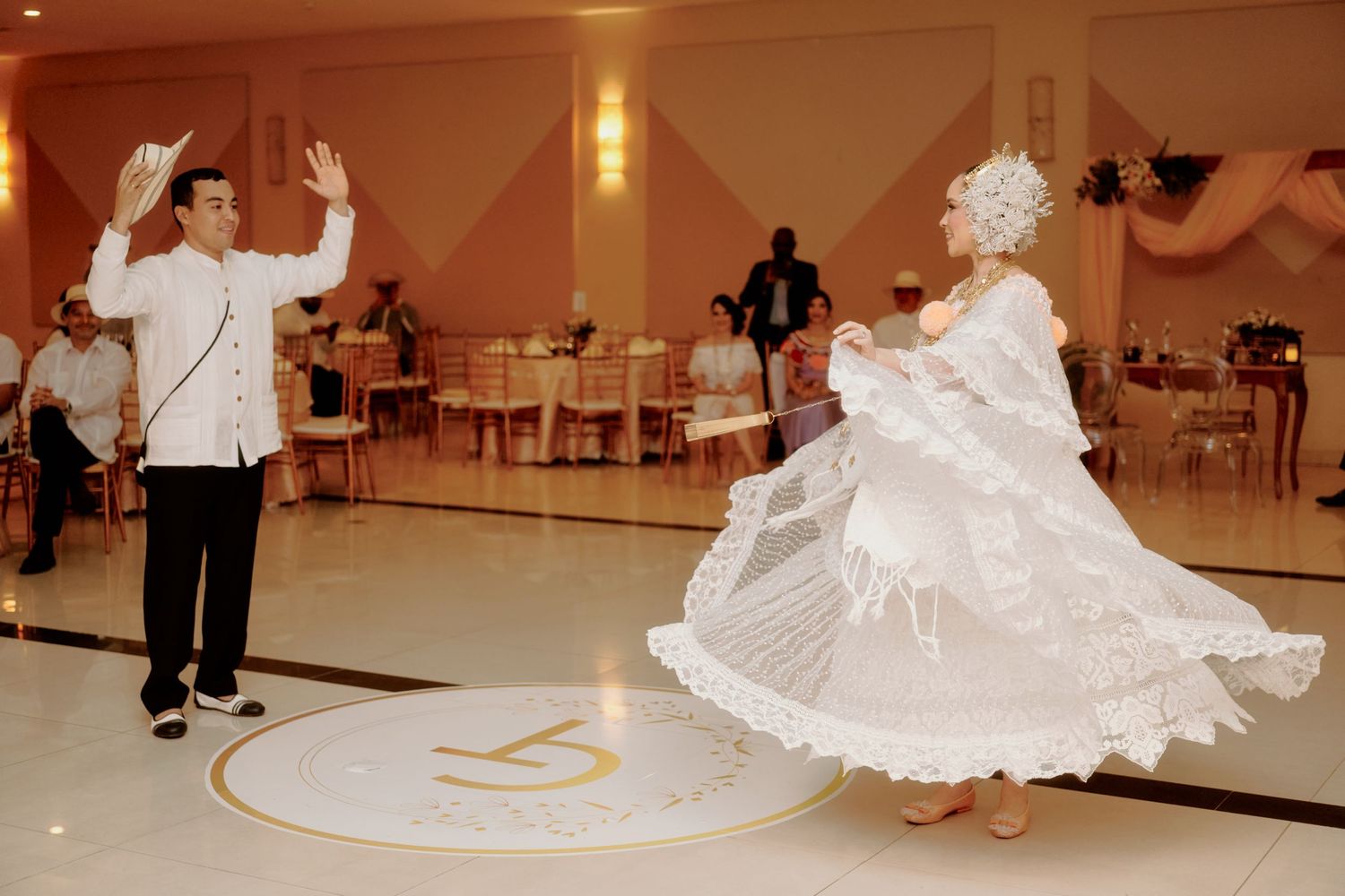 Dancers perform an elegant twirl in traditional formal attire on a polished ballroom floor.