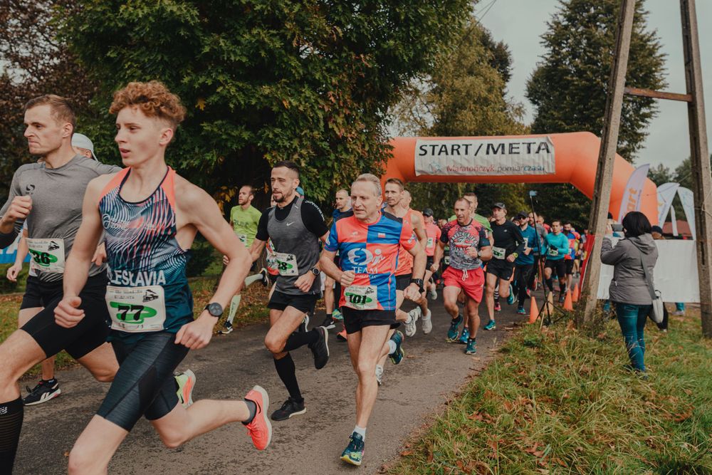 Runners racing along a tree-lined path during an autumn marathon event.