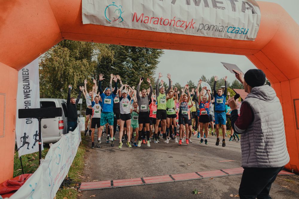 Runners gathered under orange inflatable arch at race starting line.