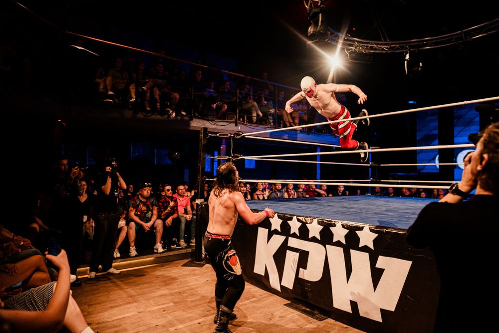 A high-flying wrestling move being performed in front of an excited crowd at an MPW event.