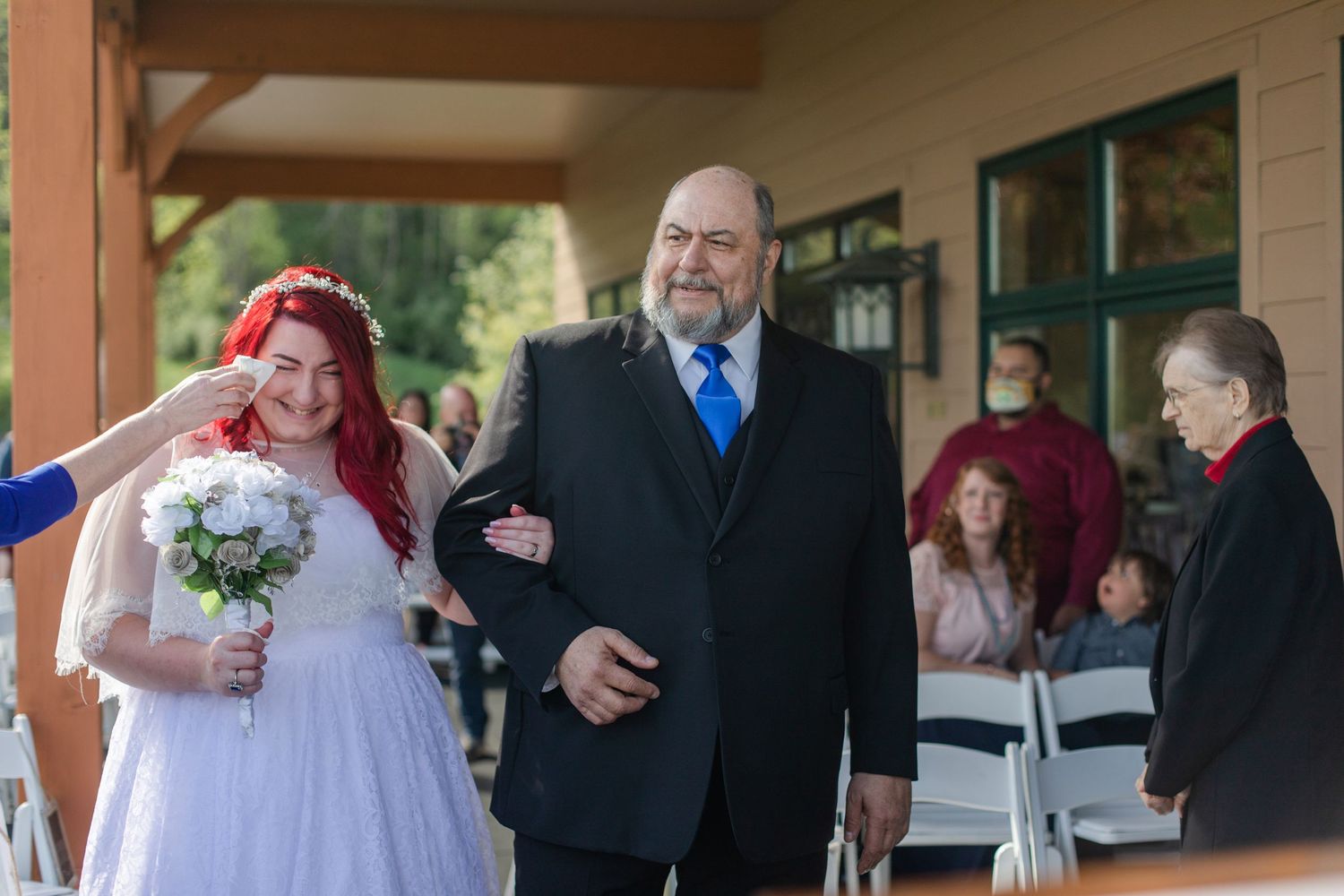 Wedding attendees gathered under a covered porch during an outdoor ceremony.