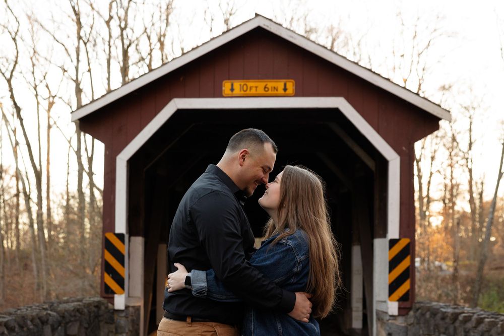 A couple embraces inside a wooden covered bridge during an autumn afternoon.