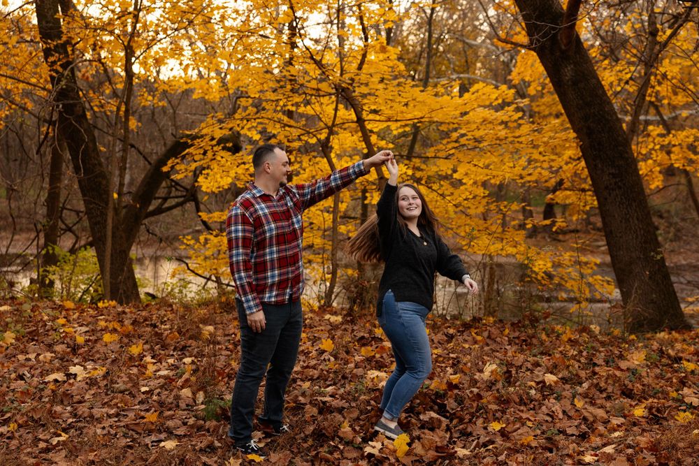 A joyful autumn photoshoot with dancing and laughter among fallen leaves.